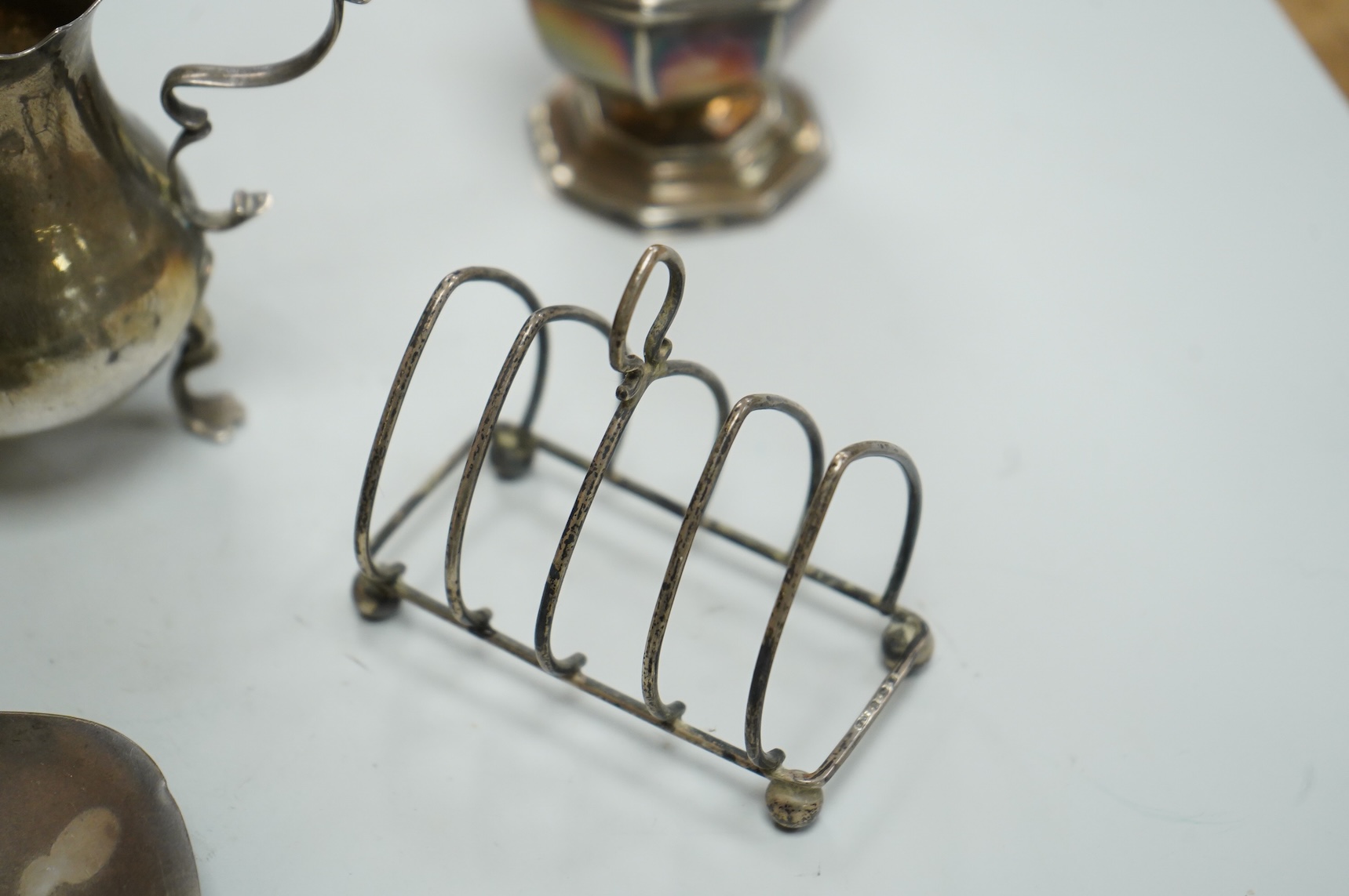 A collection of small silver, including a George III cream jug, London, 1762, 88mm, a George V sugar caster, small five bar toastrack, pair of bonbon dishes, pepperette, dish, two condiment spoons and mustard pot, togeth